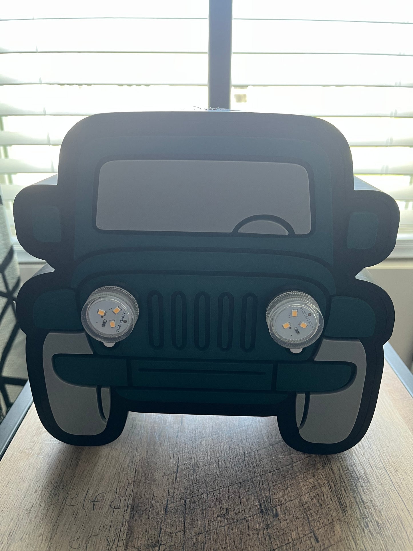 Green car-shaped object on a wooden surface with a blurred background