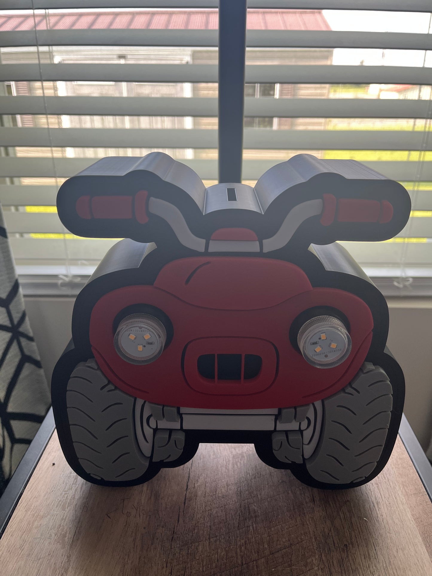 Toy car-shaped object on a wooden surface with a window in the background